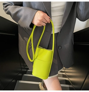 Close-up of neon green pebble grain PU leather mini bucket bag with front pocket detail