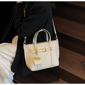 Detail of creamy litchi grain leather tote bag with gold buckle and matching charm