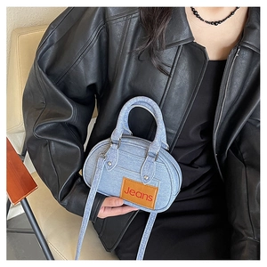 Close-up of light blue denim bowling bag with a leather Jeans patch and adjustable strap