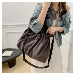 Detalle de bolso hobo gris oscuro con cordón mostrado con un atuendo casual de tendencia