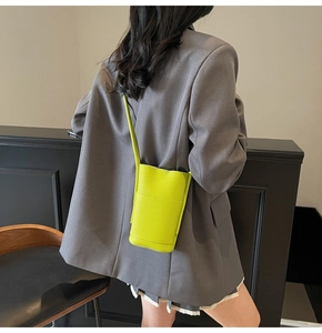 Detail of lime green litchi texture small crossbody phone bag on a grey blazer outfit