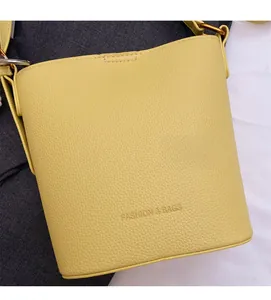Detail of yellow lychee texture leather bucket bag with fashion logo and metal strap ring