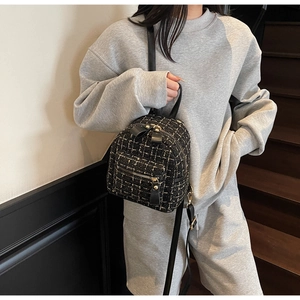 Mini zaino in tweed bianco e nero con dettagli dorati mostrato indossato dal modello
