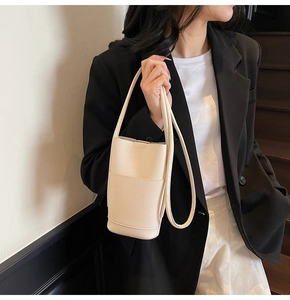 Close-up of cream white lychee texture bucket bag worn by model in minimalist outfit