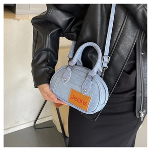 Close-up of small denim bowling bag with white stitching and leather Jeans label