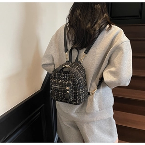 Dettaglio mini zaino in tweed con fiocco in pelle nera e finiture metalliche dorate