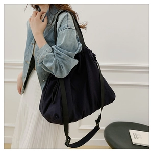 Detalle del bolso hobo de nailon negro con cierre de cordón y correa ancha
