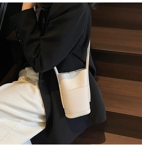 Close-up of white lychee pattern PU leather bucket mobile bag with slender shoulder strap