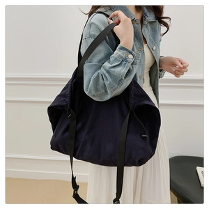 Detalle del bolso hobo azul oscuro que muestra el cordón y la correa negra ajustable