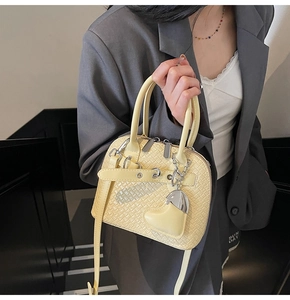 Detail view of woven texture on pale yellow PU shell bag with silver heart pendant charm