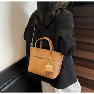 Detail of lychee pattern leather tote bag with mini purse pendant in brown yellow