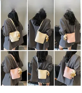 Detail view of lychee pattern bucket bag with cute plush bear charm and thin shoulder strap