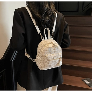 Dettaglio dello zaino in tweed crema con fili dorati e cinghie in pelle indossato da modella
