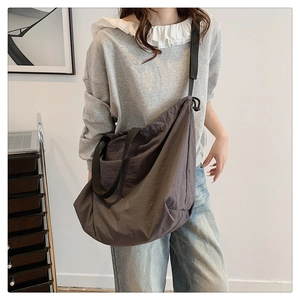 Vista detallada del bolso bandolera gris oscuro de gran capacidad usado por una modelo mujer