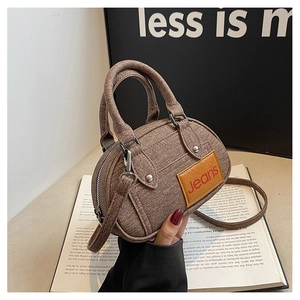 Detail of brown denim texture bowling bag with yellow jeans tag and dual handles