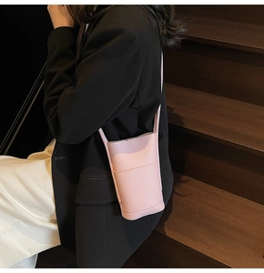 Pink lychee texture crossbody phone bag styled with a minimalist outfit on wooden stairs