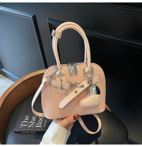 Detail of pink faux crocodile shell bag with heart charm and silver metal zippers