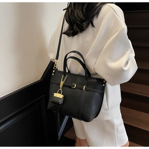 Close-up of black lychee leather tote bag with gold hardware and mini coin purse detail