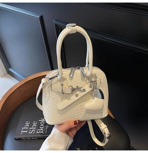 Detail of cream white faux leather bag with crocodile texture and silver heart pendant