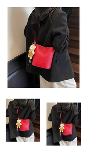 Detail of red lychee pattern bucket bag featuring a cute teddy bear plush charm