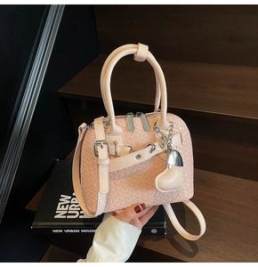 Detailed view of pink woven shell bag with adjustable strap and silver heart charm
