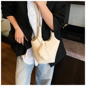Detail einer beigen Beuteltasche aus Lederimitat mit Mini-Tasche an einem Modell im Alltag