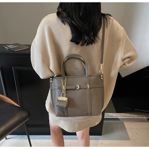 Detail of taupe lychee texture leather tote bag with gold chain coin purse and long strap