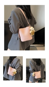 Detail view of pink lychee textured bucket bag with cute bear pendant and logo print