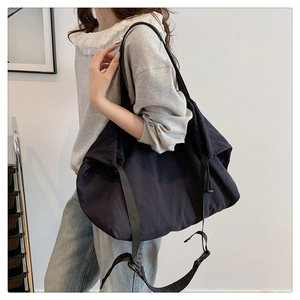 Vista lateral del bolso hobo de nailon azul marino de gran capacidad con correa tejida