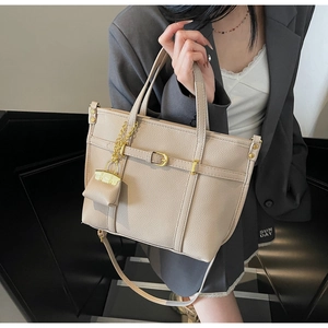 Detail of beige lychee pattern tote bag with gold hardware and mini coin purse pendant