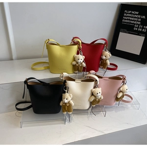 Litchi texture bucket bag details showing five vibrant colors and bear plush charm