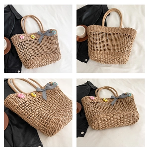 Detail of straw tote bag featuring 3D floral accents and checkered bow decoration