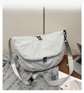 Detail of light grey crescent tote bag with MG logo, durable nylon fabric and black zipper