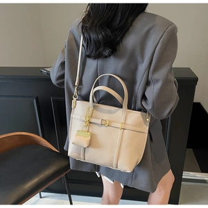 Detail of beige lychee texture handbag worn by model with matching coin purse charm