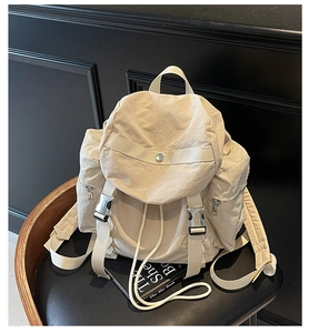 Detailed view of cream nylon backpack with silver buckles on a black chair