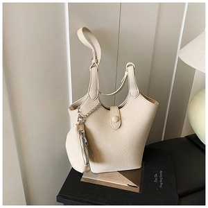 Detail der cremefarbenen Tragetasche mit runder Münztasche und glänzender Metallkette