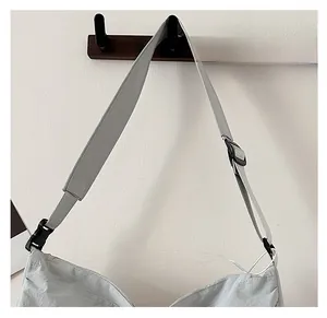 Detail of adjustable wide shoulder strap with plastic buckle on gray travel tote bag