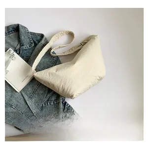 Detail shot of the ruffled strap and wrinkled texture on an off-white crescent bag