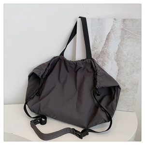 Detalle del cierre con cordón y hebilla ajustable en el bolso hobo de nailon gris oscuro