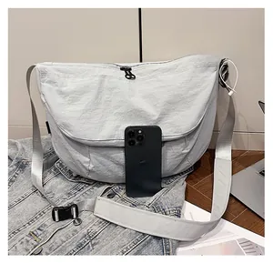 Detail of light grey nylon sling bag with MG logo and adjustable strap showing size scale