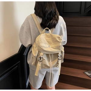 Beige nylon backpack with drawstring and metal buckle closure shown on model