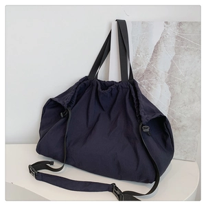 Detalle del bolso hobo grande de nailon azul oscuro con cierre de cordón y hebilla de plástico