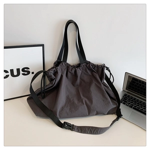 Detalle del bolso tote grande de nailon gris oscuro con correa ajustable y cierre de cordón