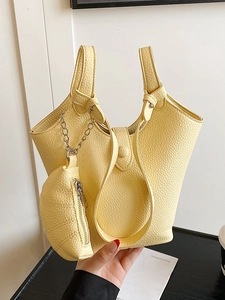 Minimalistische hellgelbe Eimertasche aus genarbtem Leder mit passender Münzbörse