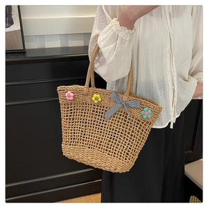 Detail of hand-woven straw basket bag featuring floral accents and a gingham bow accessory