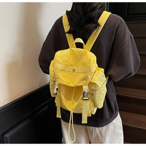 Detail of yellow nylon backpack with metal buckle and drawstring closure on a model
