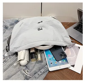 Spacious light gray nylon crescent bag detail showing interior storage for tablet and umbrella