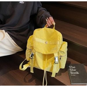 Detail view of bright yellow nylon backpack with buckle closures on wooden stairs