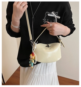 Detail of cream white leather handbag with colorful cartoon charms and pearl strap