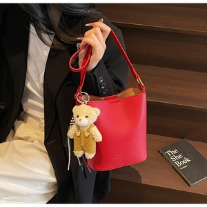 Red lychee texture bucket bag with a cute teddy bear charm for stylish commute outfits